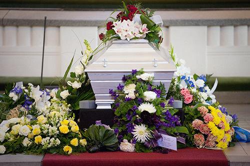 Kista med blommor runt sig i kyrkan under en begravning