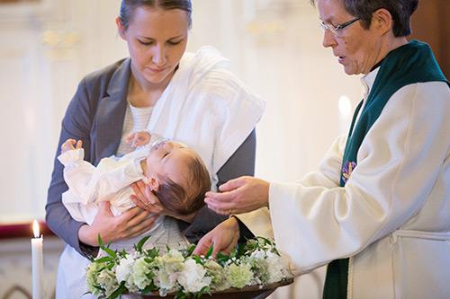Bebis blir döpt av präst